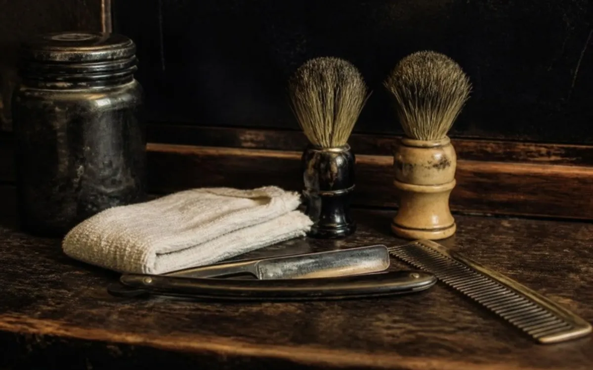 Navalha, pincéis de barba e toalha sobre uma bancada de madeira